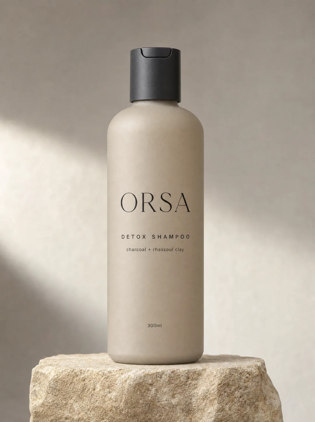 ORSA detox shampoo, a taupe bottle with a black cap on a stone ledge